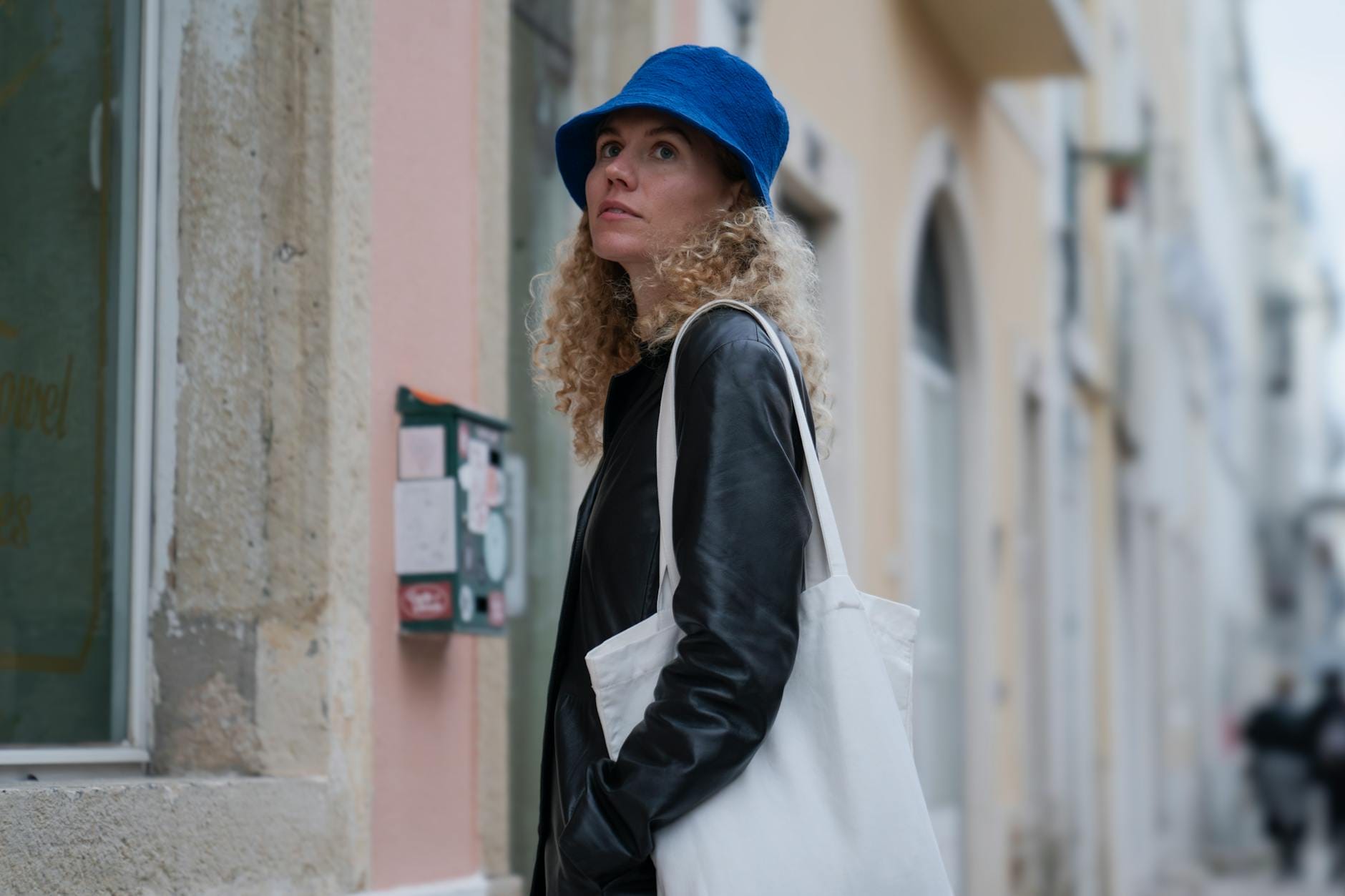 Kobieta w niebieskim kapeluszu idzie ruchliwą ulicą miasta