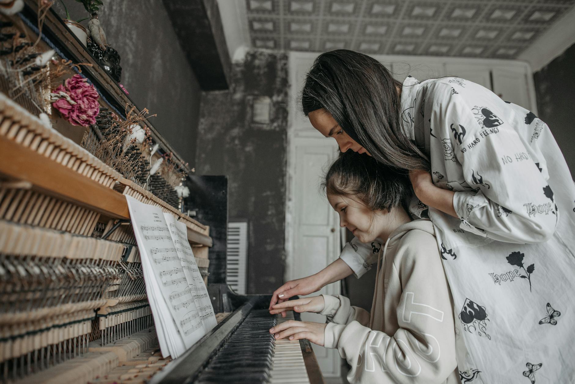 Mama uczy córkę gry na pianinie w domowym, przytulnym wnętrzu vintage
