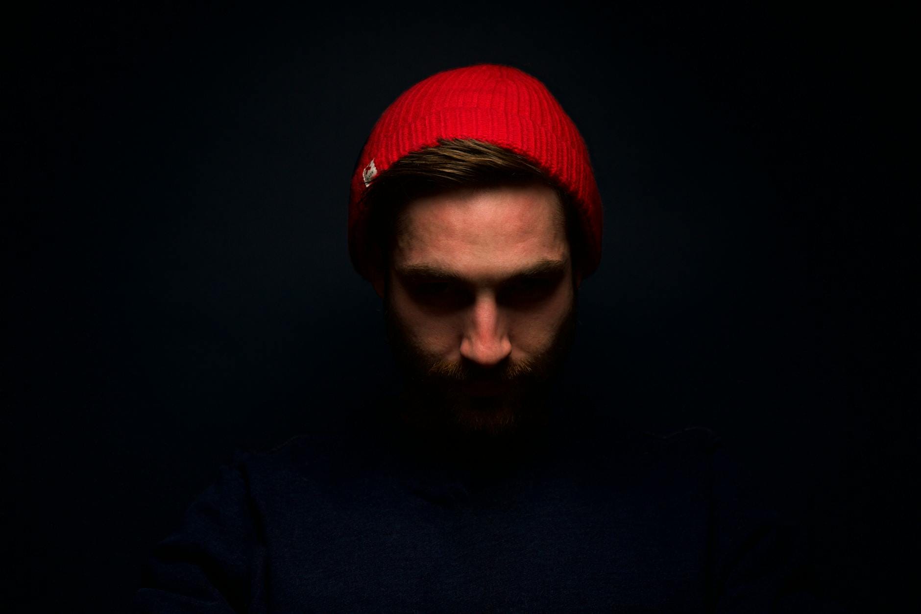Mężczyzna w czerwonej czapce beanie w cienistym, nastrojowym portrecie