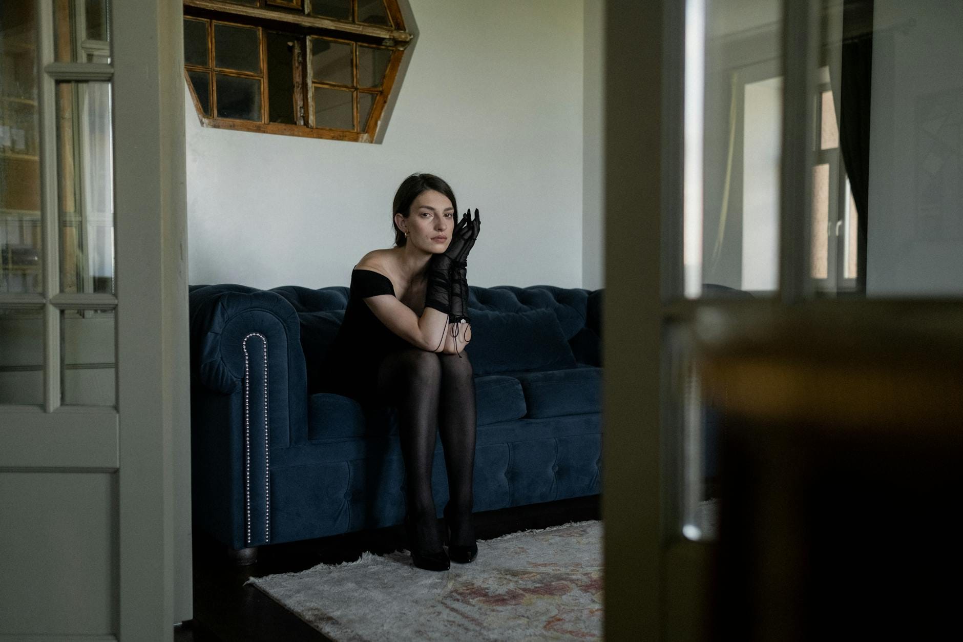 Kobieta w małej czarnej siedzi zamyślona na sofie