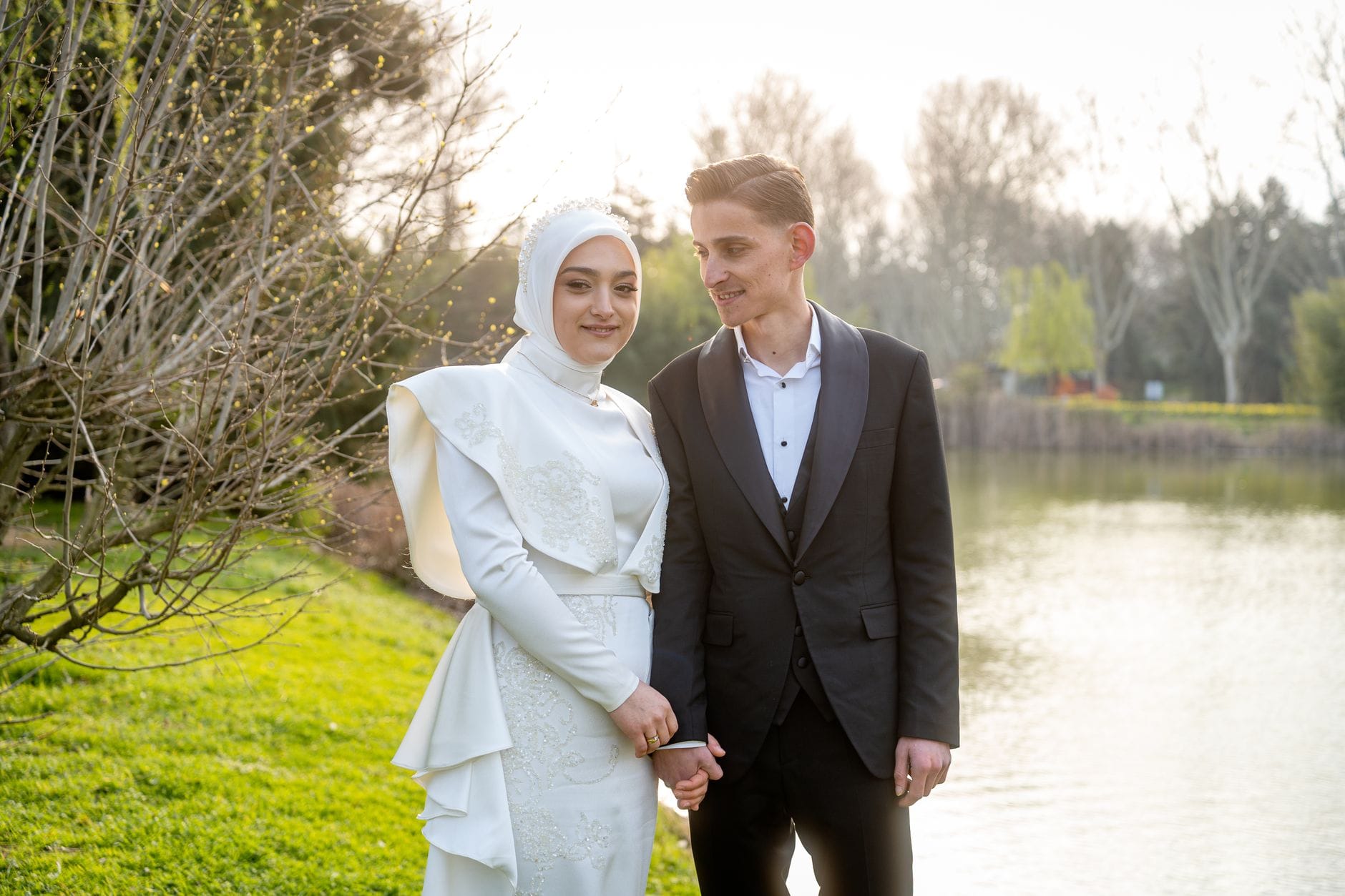 Para w eleganckich strojach ślubnych nad wiosennym jeziorem