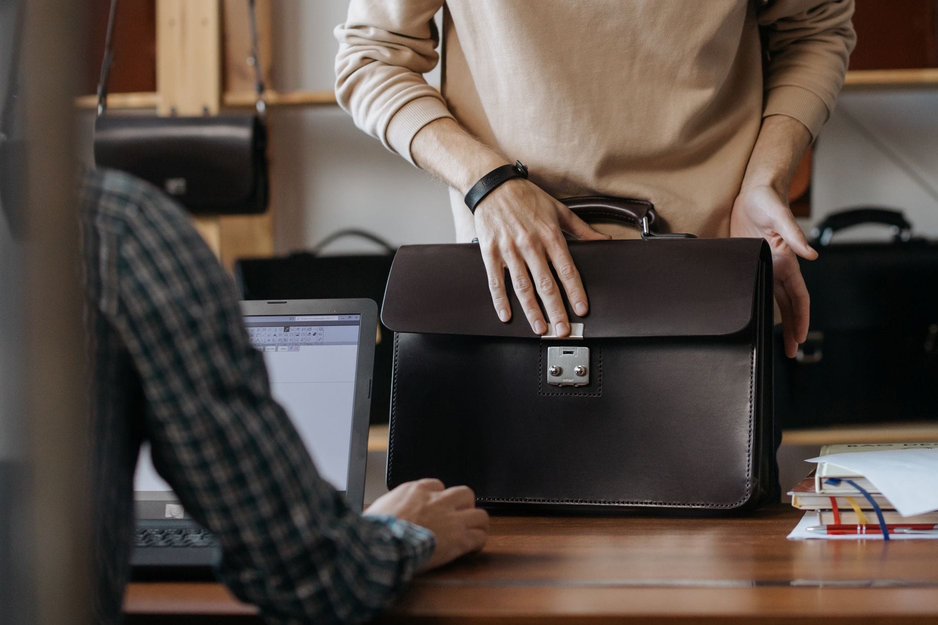 Dwie osoby trzymają skórzaną torbę na laptop w biurze